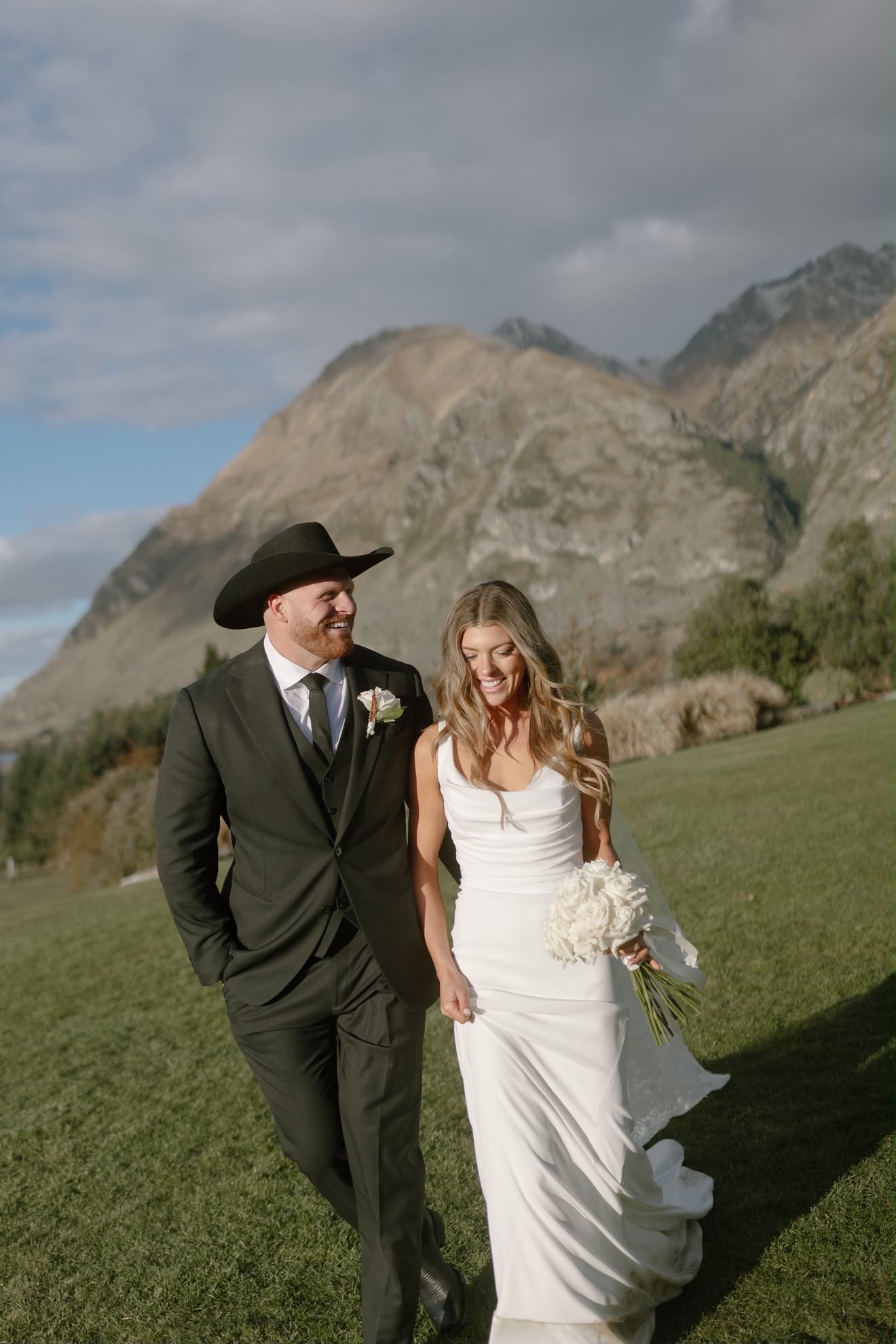 Bride and groom walking across the lawn, mountains behind