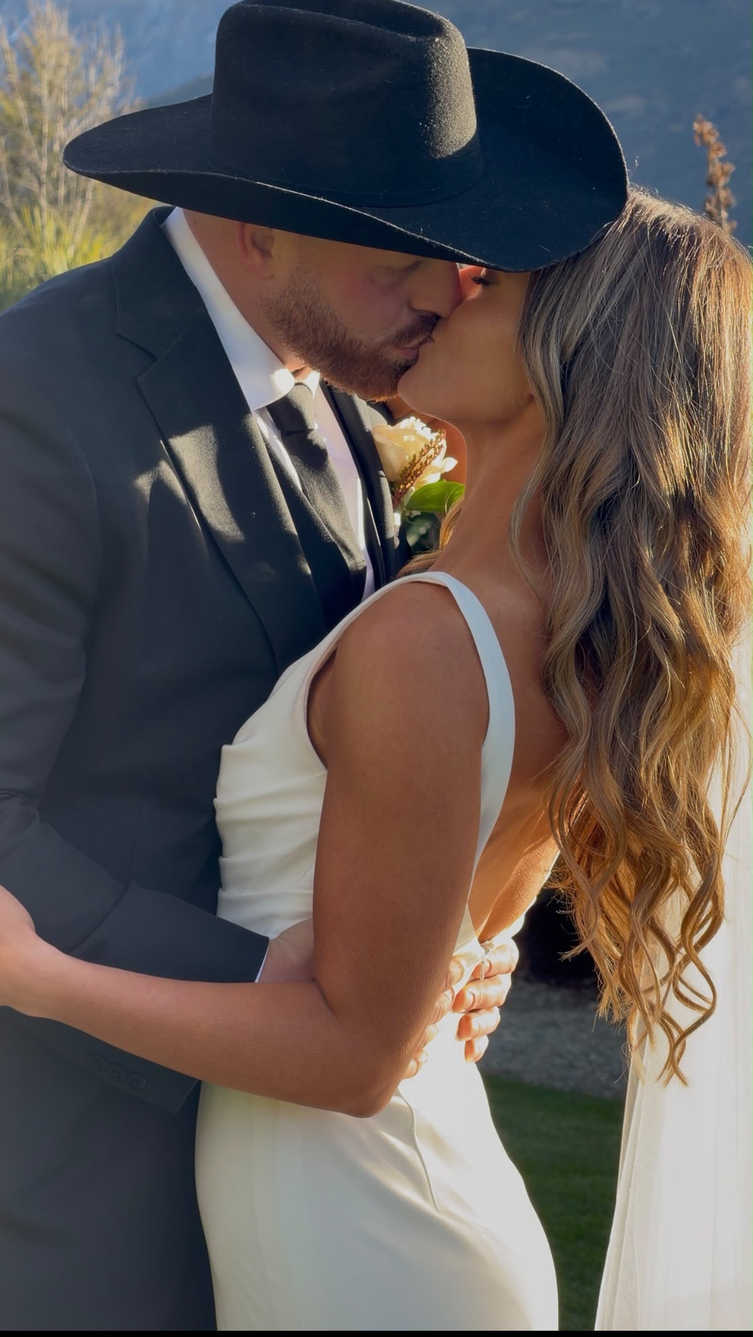 Bride and groom sharing a kiss, groom in a black hat