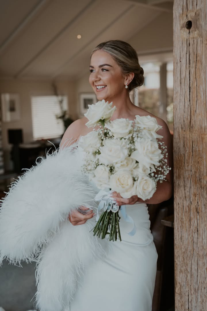 Bride with a feather stole and white rose bouquet