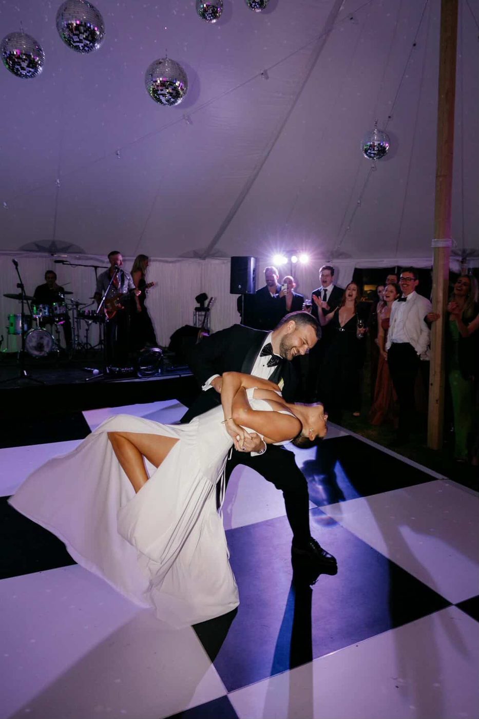 Groom dipping the bride during their first dance on a checkered floor
