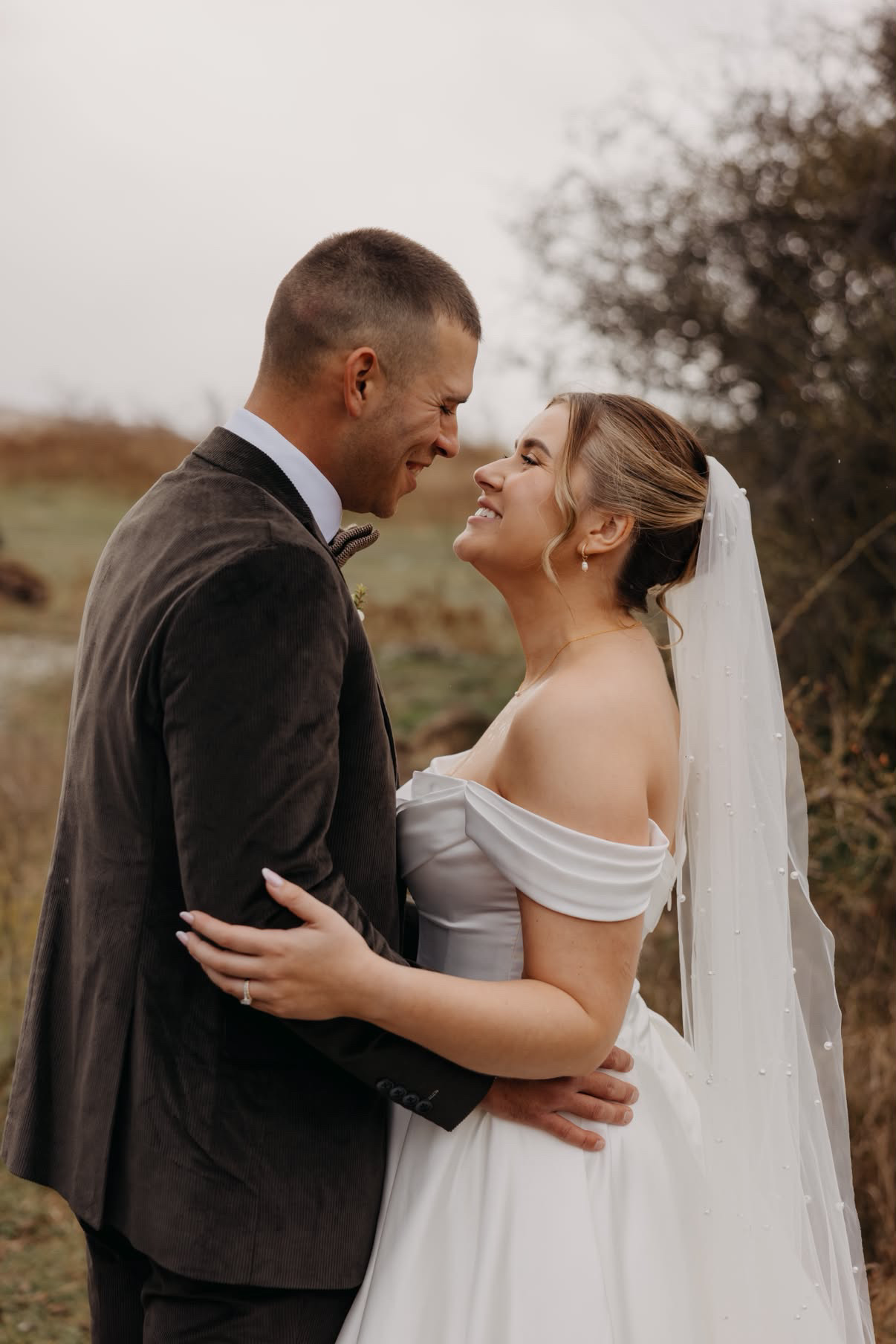 Bride and groom embracing in the field