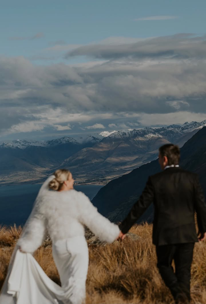Bride and groom walking hand in hand toward the mountains