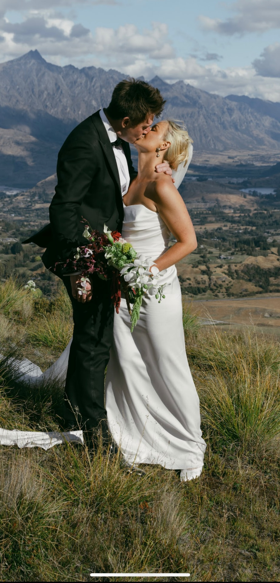 Bride and groom kissing in front of The Remarkables