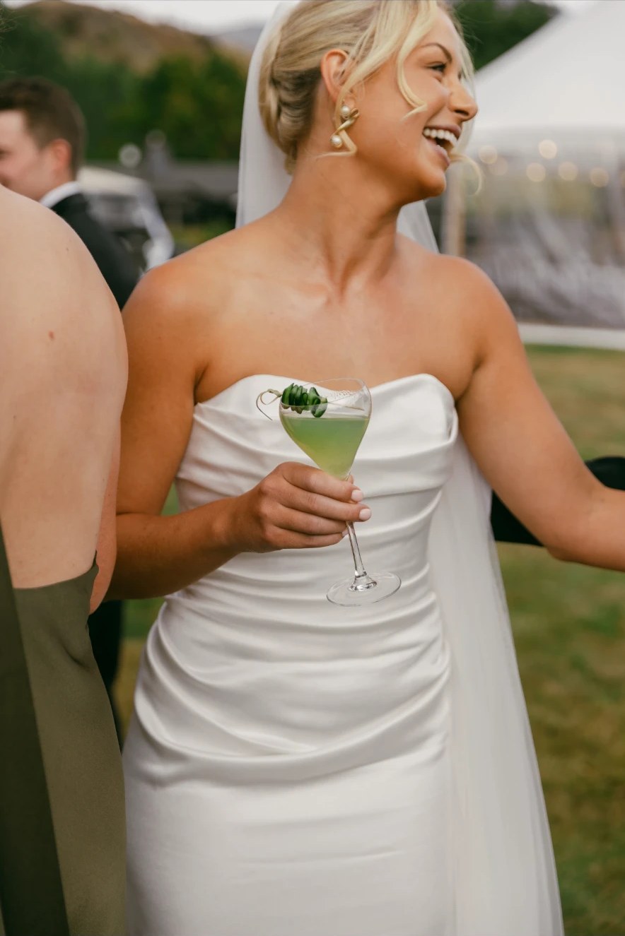 Bride laughing with a cocktail at her outdoor reception