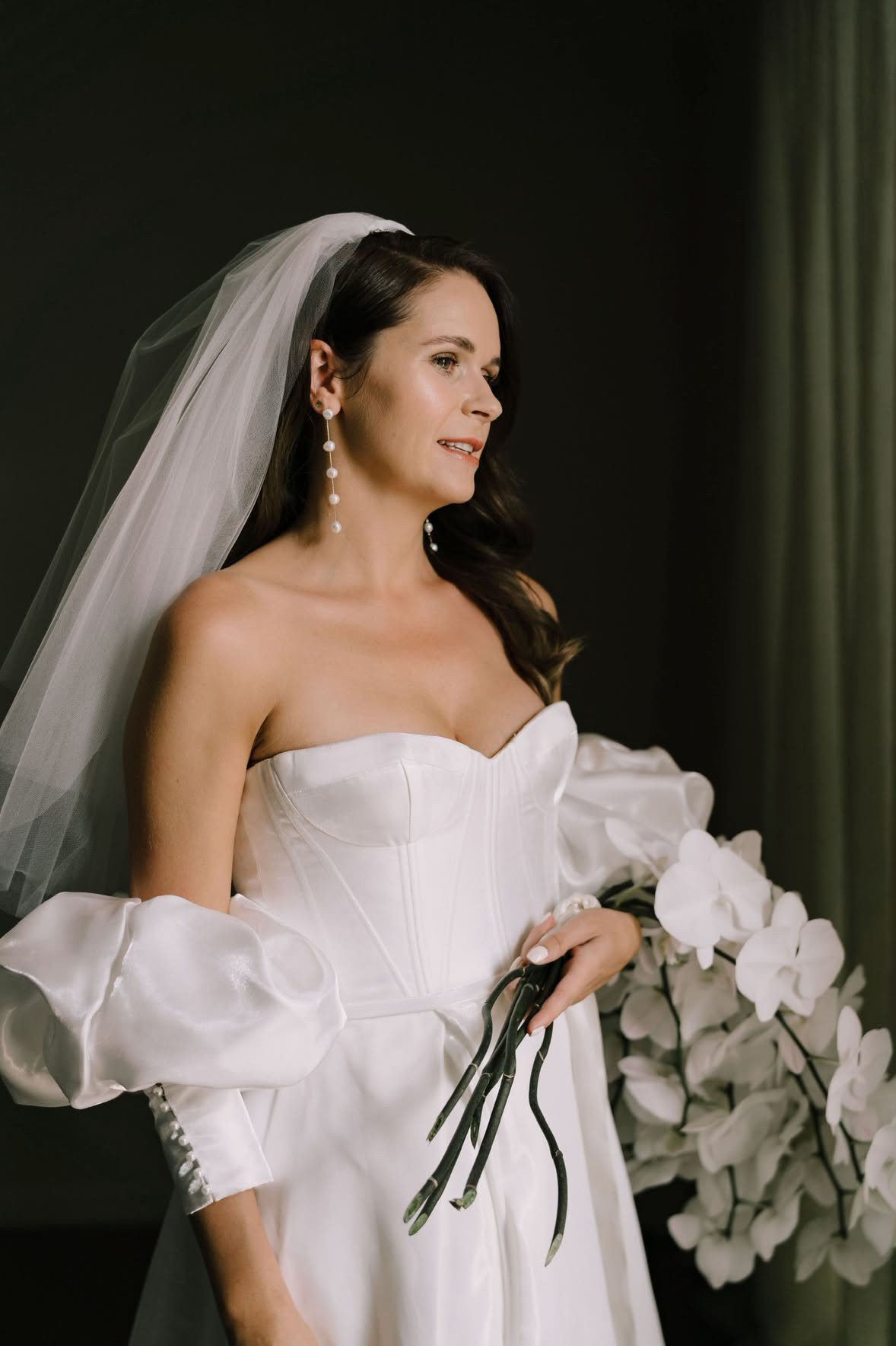 Bride in pearl earrings holding her orchid bouquet