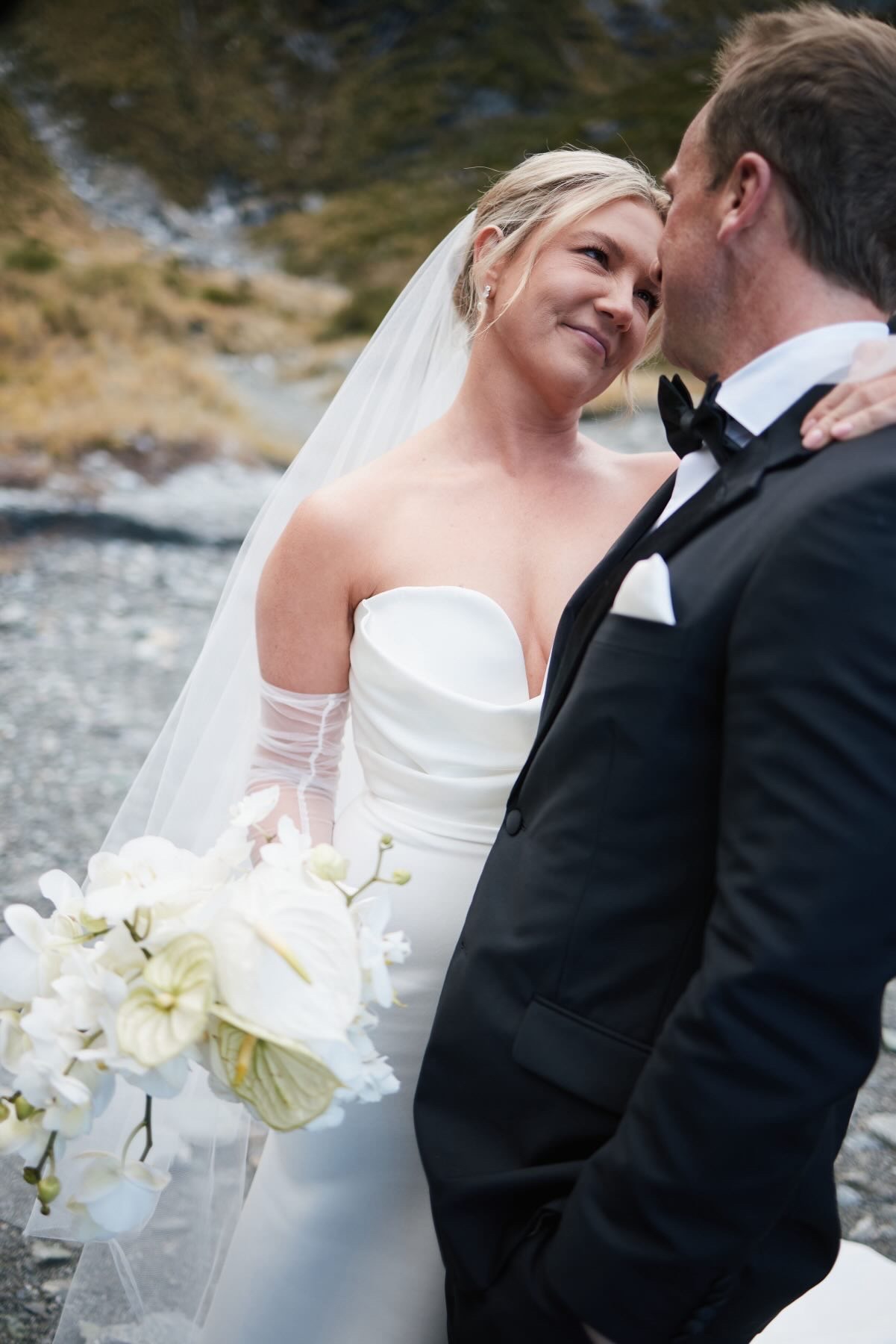 Bride and groom forehead to forehead by the river