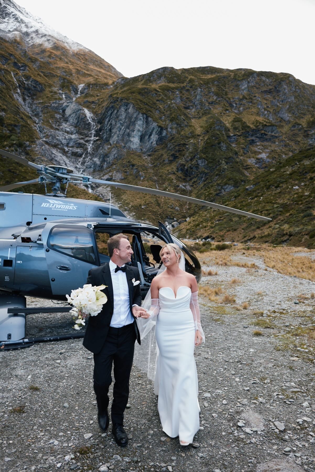 Bride and groom walking from the helicopter in the mountains