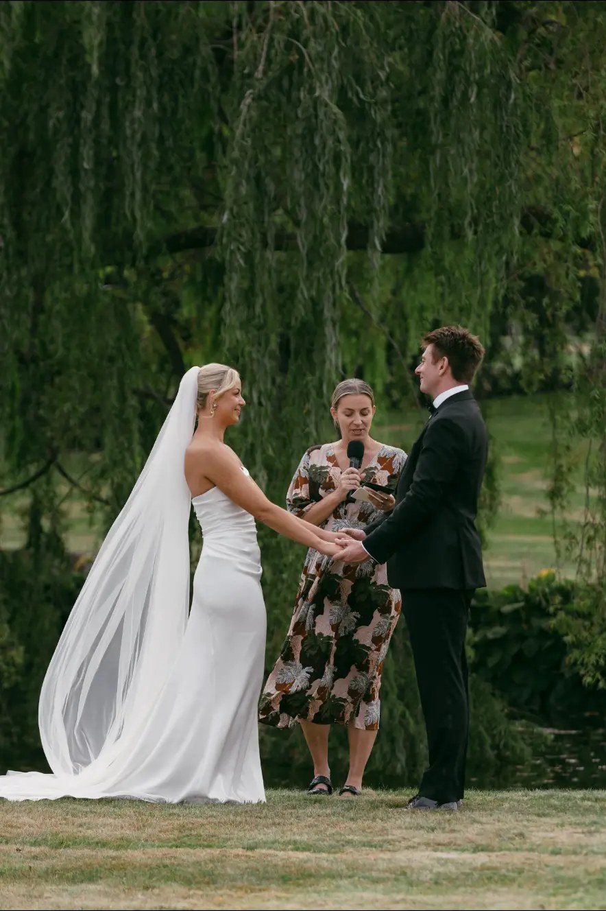 Bride and groom holding hands during their outdoor ceremony