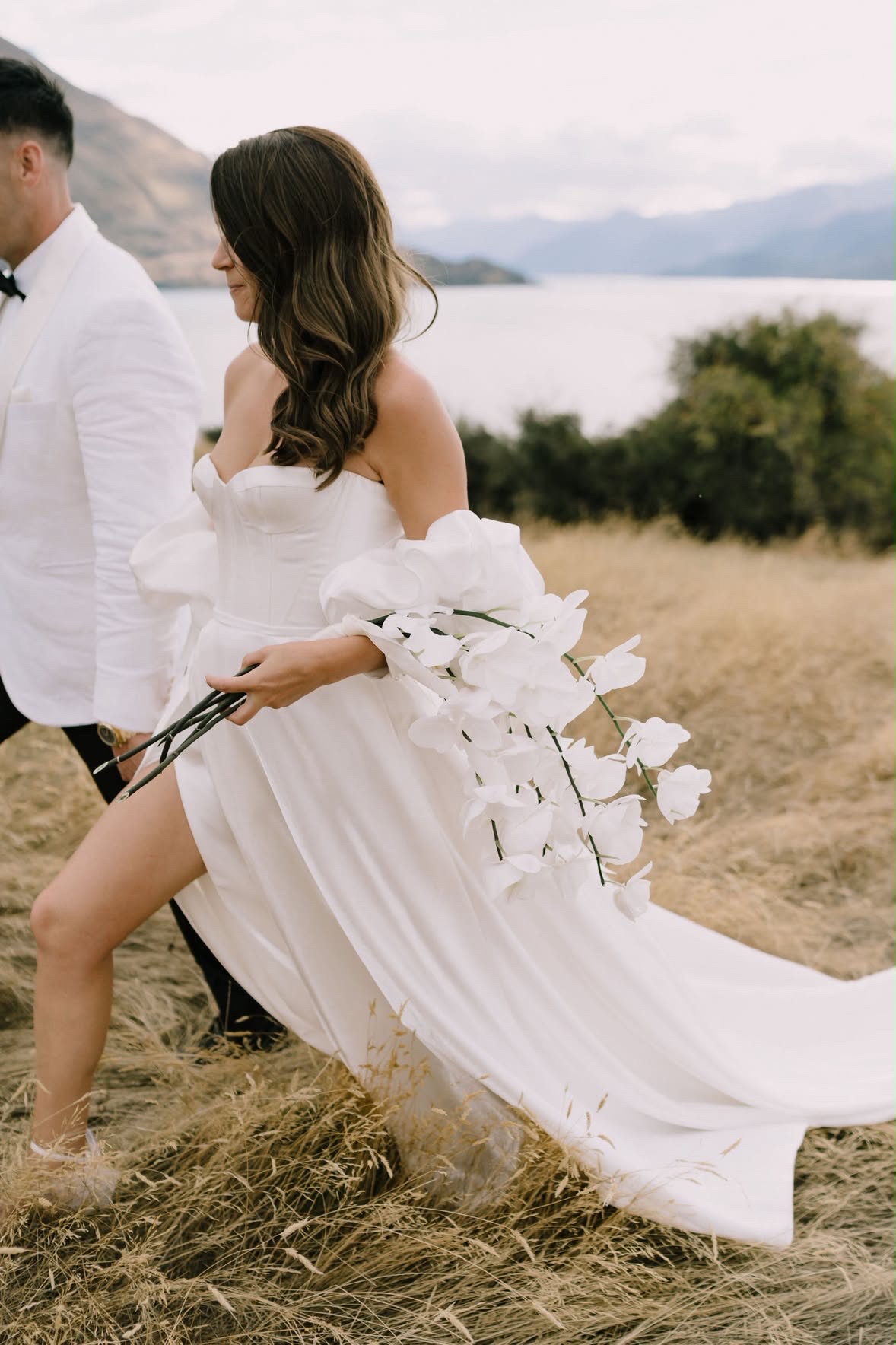 Bride striding through the tussock with her bouquet