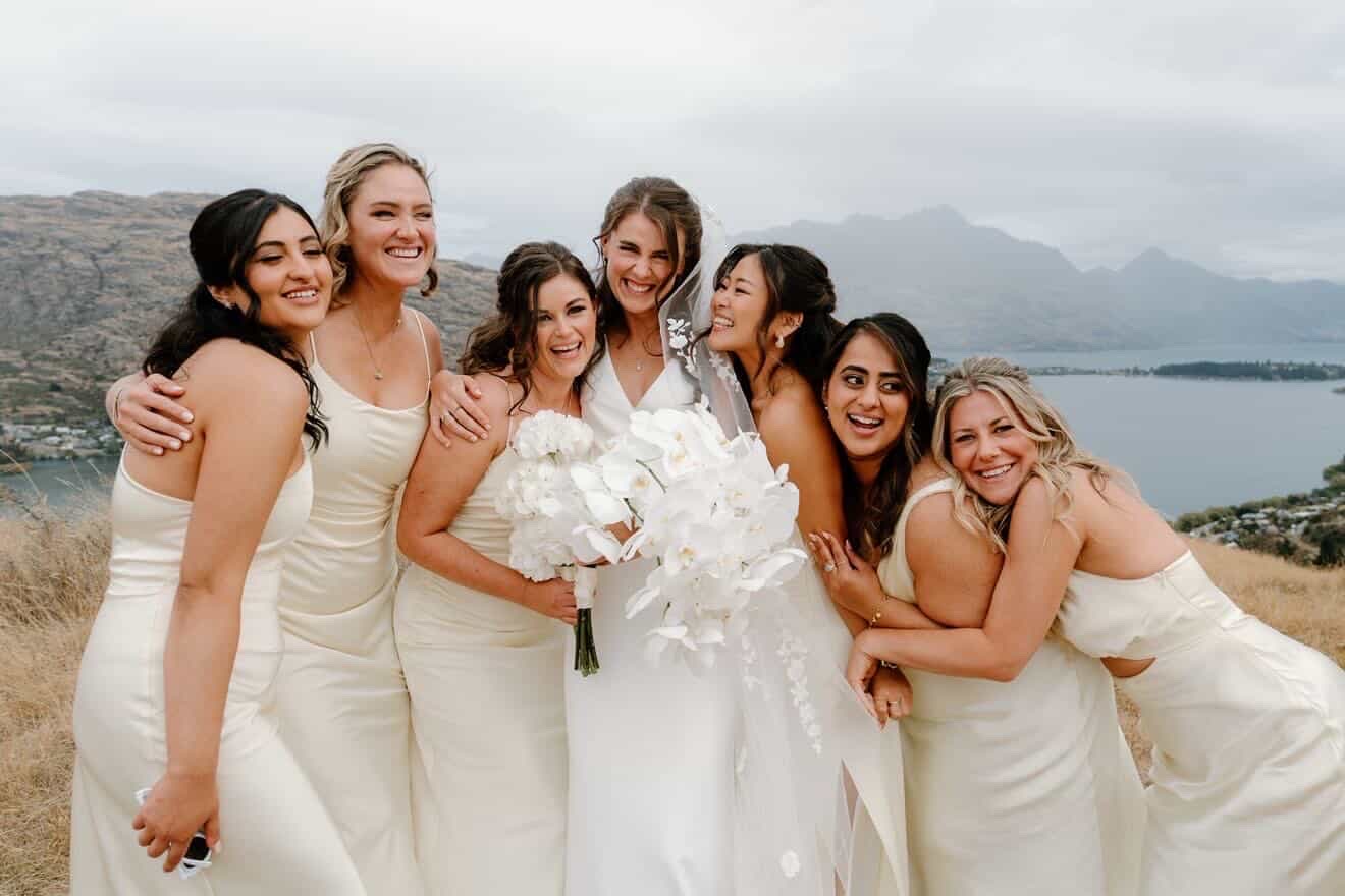 Bride laughing with her bridesmaids above the lake
