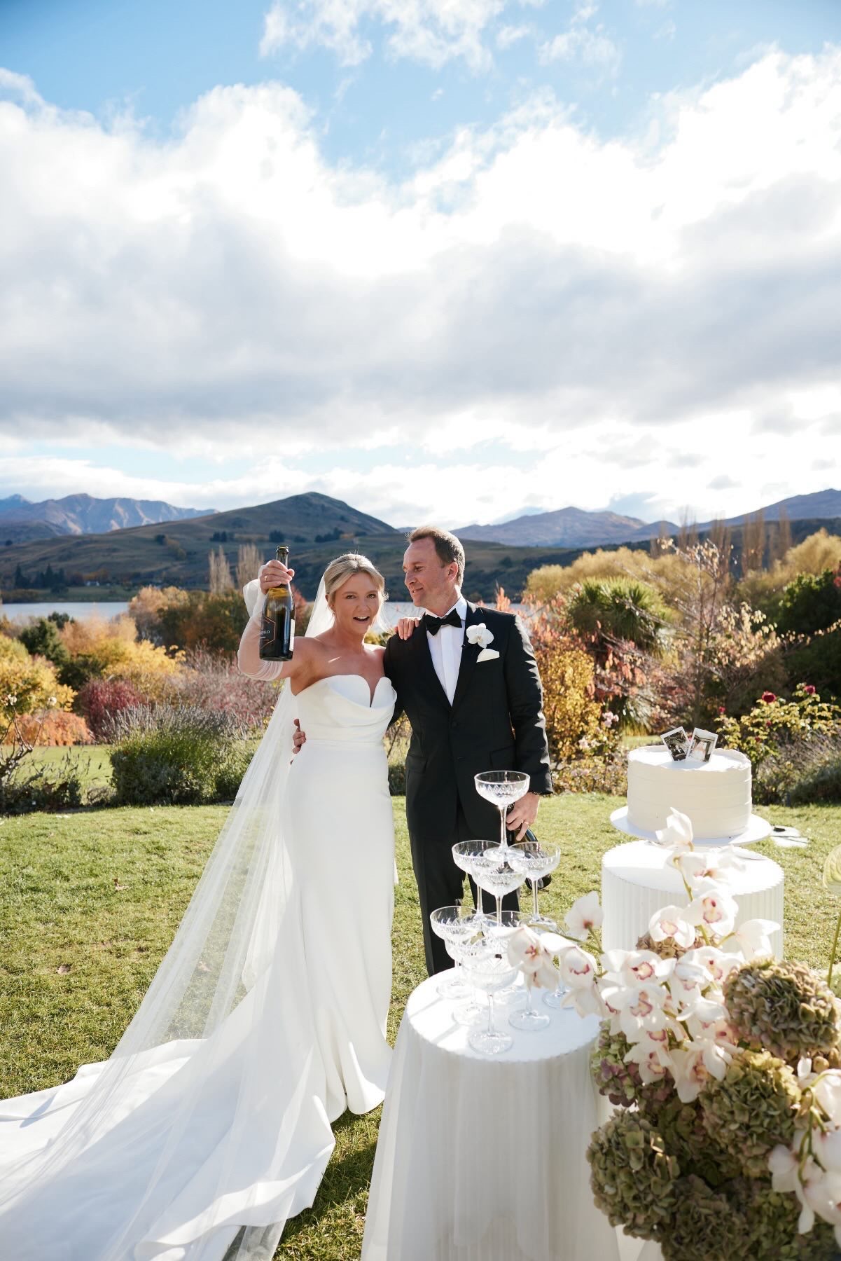 Bride and groom with the champagne tower in the garden