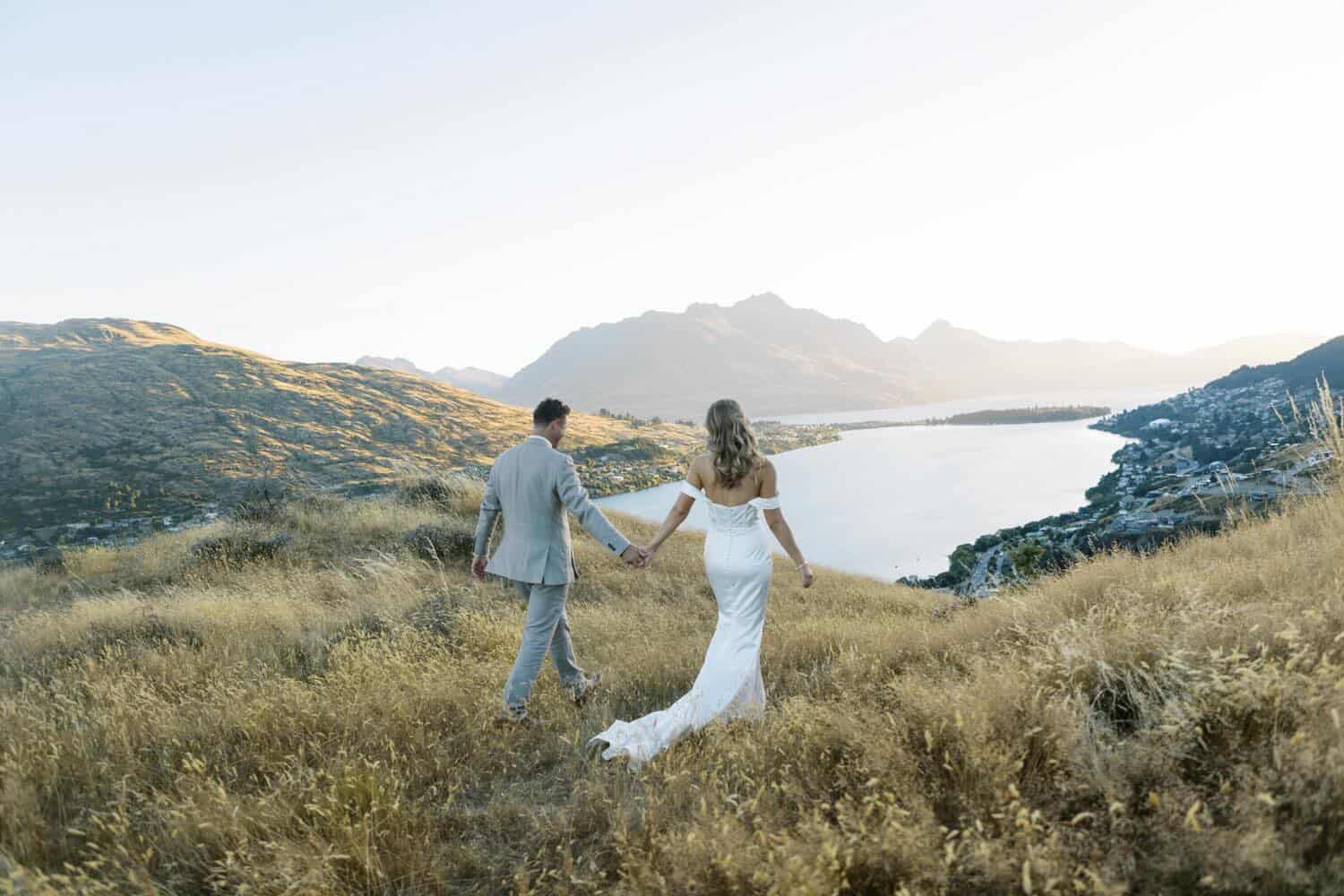 Couple walking through golden tussock above Queenstown