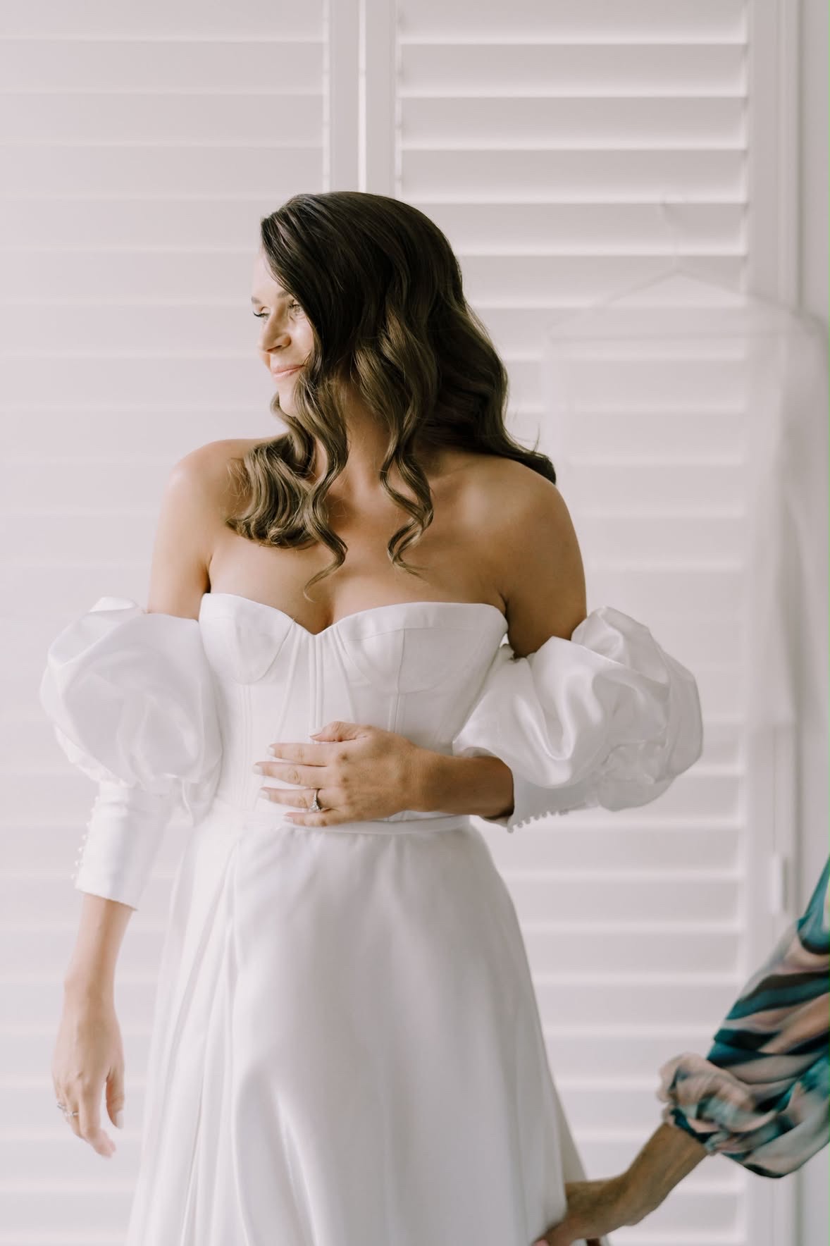 Bride having her dress finished by the shutters