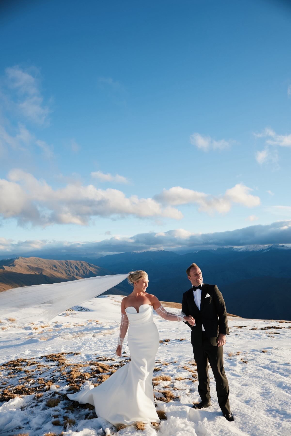 Bride and groom walking across the snowy ridge
