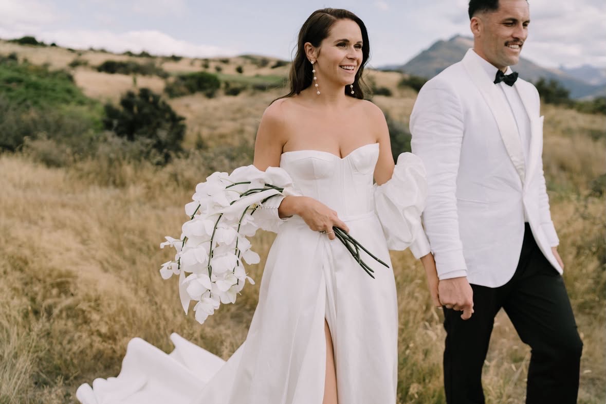Bride and groom walking through the golden grass