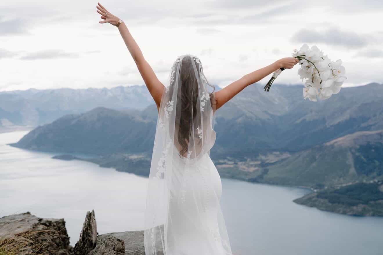 Bride with arms raised above Lake Wakatipu
